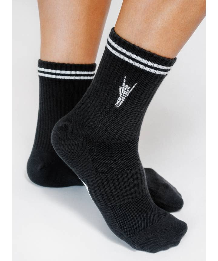 Person wearing Rock On Knit Ankle Sock By Loindaflow | Tailored Union—black ribbed ankle socks with white double stripes and a small white hand graphic, from Tailored Union.