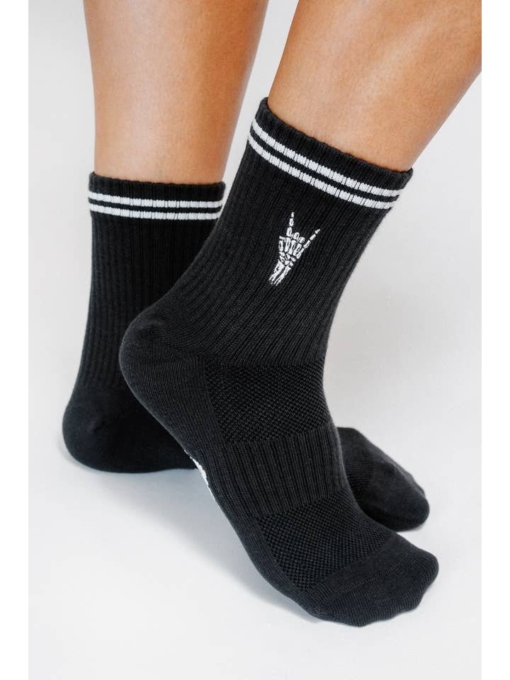 Person wearing Rock On Knit Ankle Sock By Loindaflow | Tailored Union—black ribbed ankle socks with white double stripes and a small white hand graphic, from Tailored Union.
