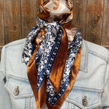 A mannequin displays the Rust & Navy Paisley Wild Rag by Rodeo Drive, tied stylishly around the neck over a light denim jacket.