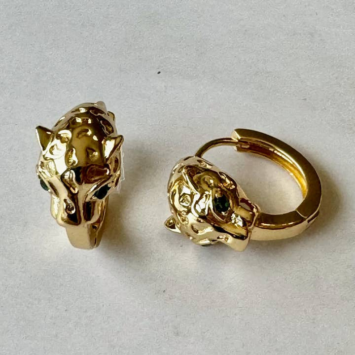 The Sabrina Earrings by Jessica Matrasko Jewelry are gold filled hoops with detailed leopard head huggies and black eye accents. Hypoallergenic for comfort and style, they're shown on a light surface.