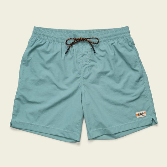 The Salado Shorts Arctic by Howler Brothers are light blue, quick-drying nylon shorts with an elastic waistband, brown drawstring, and a white logo patch on the bottom left hem, shown on a plain background.