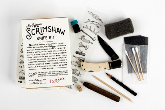 The Mollyjogger Scrimshaw Knife Kit includes a bone-handled pocket knife, folding knife, practice sheets, steel wool, fabric, cotton swabs, files, black marker, and dice—everything arranged for your scrimshaw art projects.