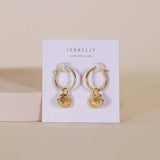 The Seashell Hoop Earrings - 18k Gold Plated by JaxKelly feature gold, shell-shaped charms on hoops, displayed on a branded card. Hypoallergenic and perfect for sensitive ears.