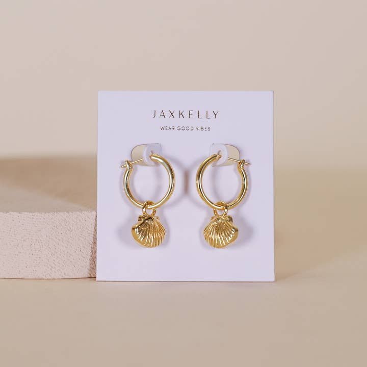 The Seashell Hoop Earrings - 18k Gold Plated by JaxKelly feature gold, shell-shaped charms on hoops, displayed on a branded card. Hypoallergenic and perfect for sensitive ears.