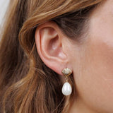 A close-up of a woman's ear wearing JaxKelly's Seashell Pearl Drop Gold Earrings, featuring a gold seashell with a dangling freshwater pearl for an elegant, tarnish-free look.