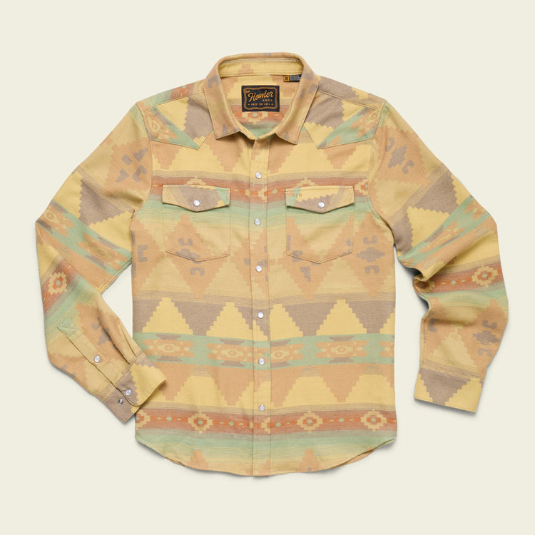The Howler Brothers Sheridan Flannel Old Gold is a long-sleeve western shirt in a yellow, green, and orange geometric southwestern pattern, made from soft cotton jacquard flannel with two chest pockets and white buttons.