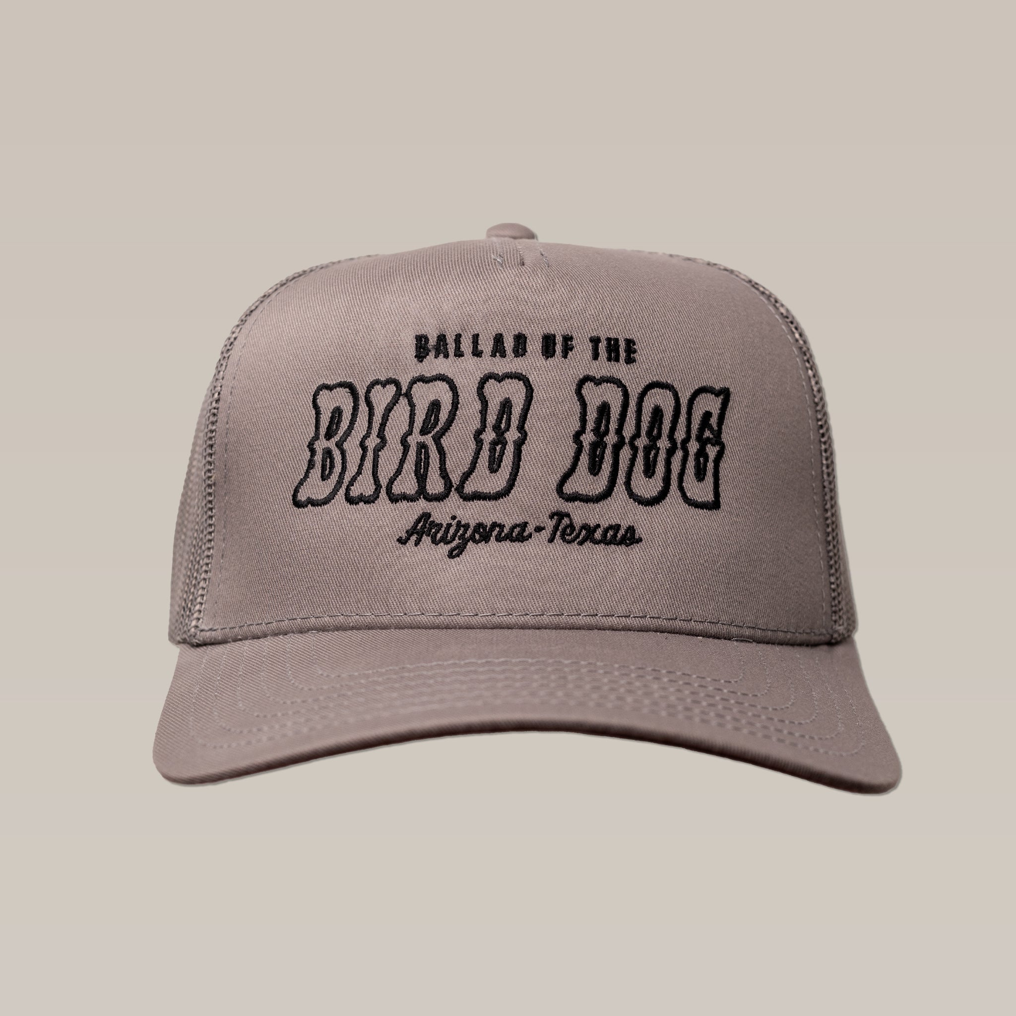 The Ballad of the Bird Dog Shop Hat | Arizona to Texas is a gray trucker hat with black embroidered "Ballad of the Bird Dog Arizona-Texas" text on the front, shown on a plain beige background.