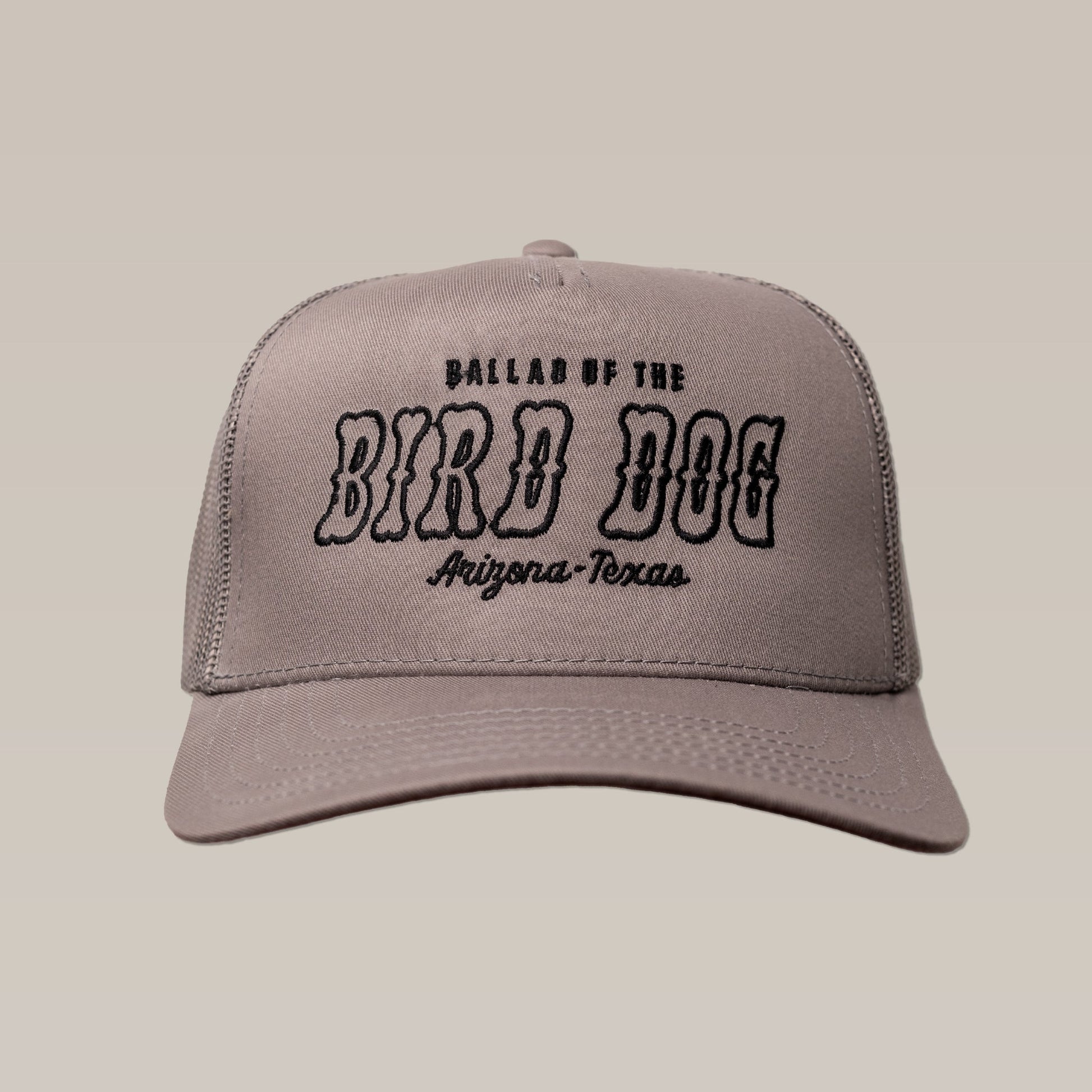 The Ballad of the Bird Dog Shop Hat features gray fabric with black “Arizona-Texas” text on the front, shown against a beige background.