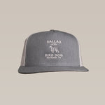 The Shop Hat by Ballad of the Bird Dog is a gray and white trucker hat with "Ballad of the Bird Dog Brenham, TX" and a dog outline embroidered on front—ideal for those who value style and comfort.