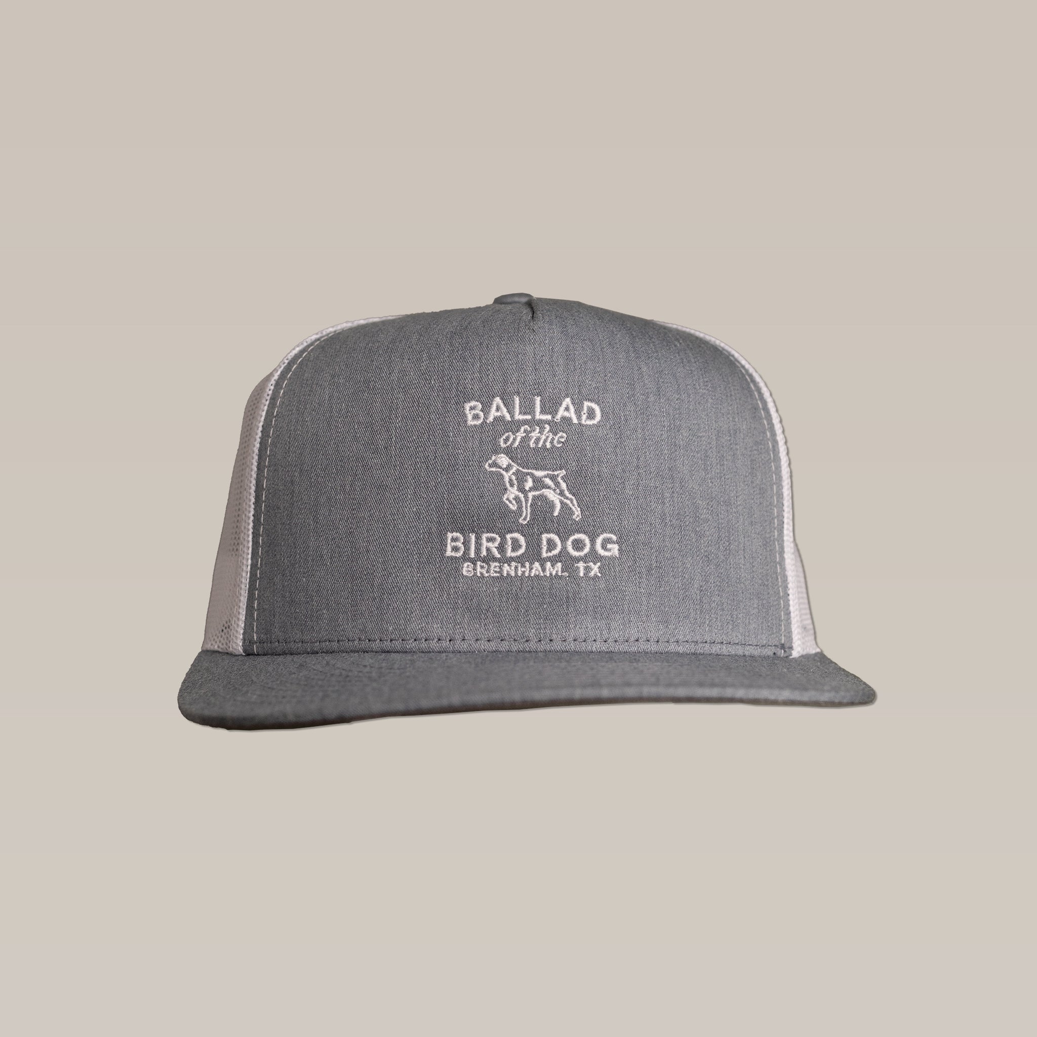 The Shop Hat by Ballad of the Bird Dog is a gray and white trucker hat with "Ballad of the Bird Dog Brenham, TX" and a dog outline embroidered on front—ideal for those who value style and comfort.