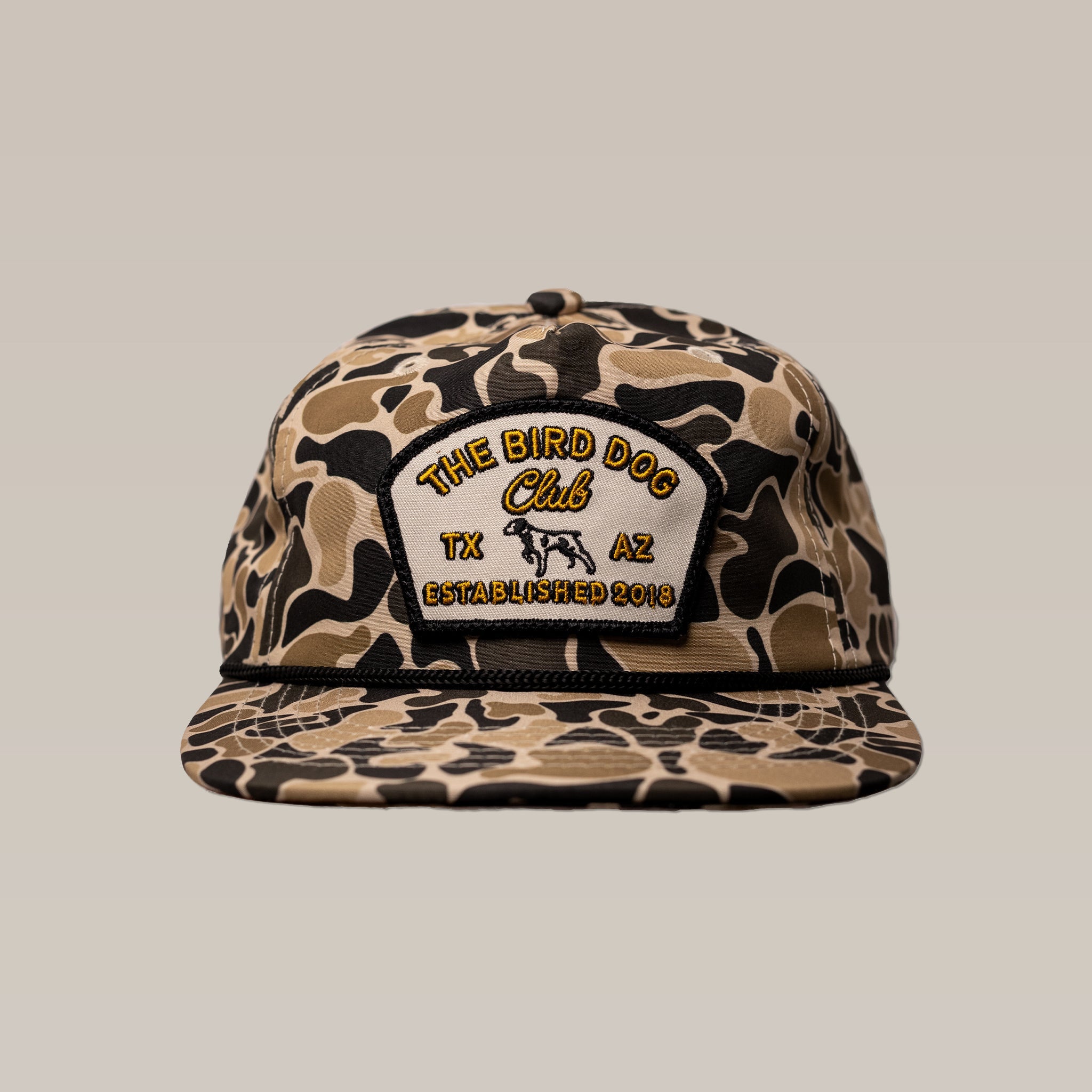 The Ballad of the Bird Dog Shop Hat | Bird Dog Club features a camouflage pattern, front patch with "The Bird Dog Club TX AZ Established 2018" and dog outline—ideal for club members and bird hunting enthusiasts.