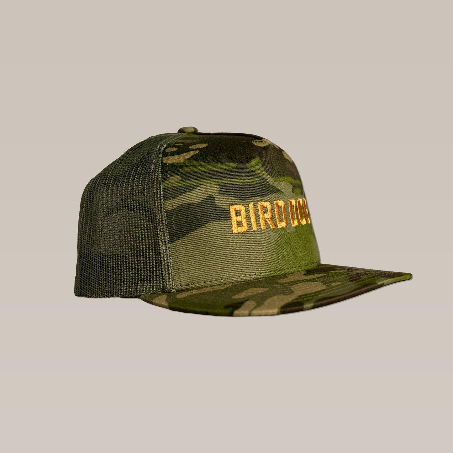 The Shop Hat by Ballad of the Bird Dog features a green camo design, breathable mesh back, and bold gold "BIRD" embroidery on the front.