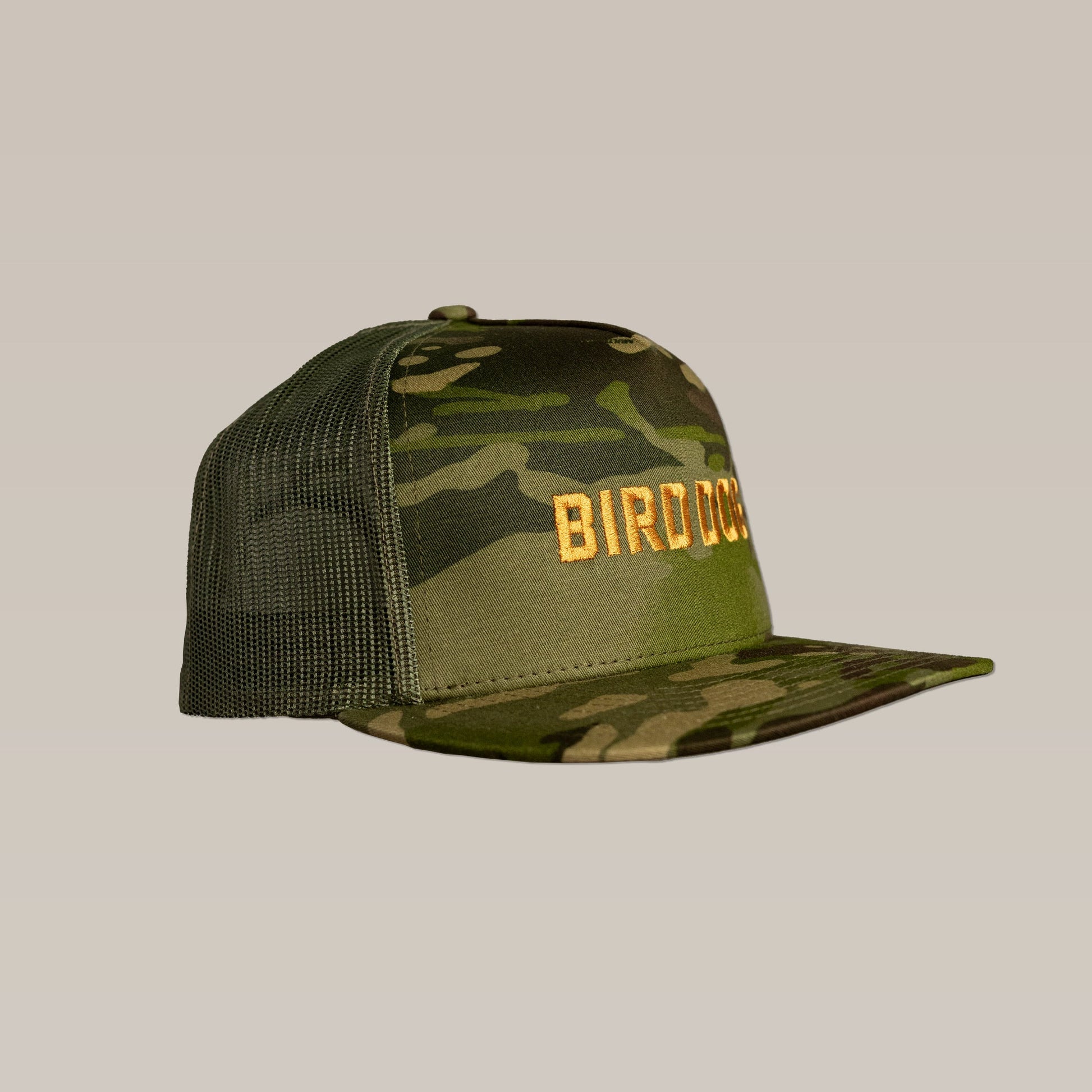 The Shop Hat by Ballad of the Bird Dog features a green camo design, breathable mesh back, and bold gold "BIRD" embroidery on the front.