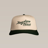 The Ballad of the Bird Dog Shop Hat features a beige crown, dark green brim, and "Brenham Texas Heritage Script | Ballad of the Bird Dog" embroidered on the front.