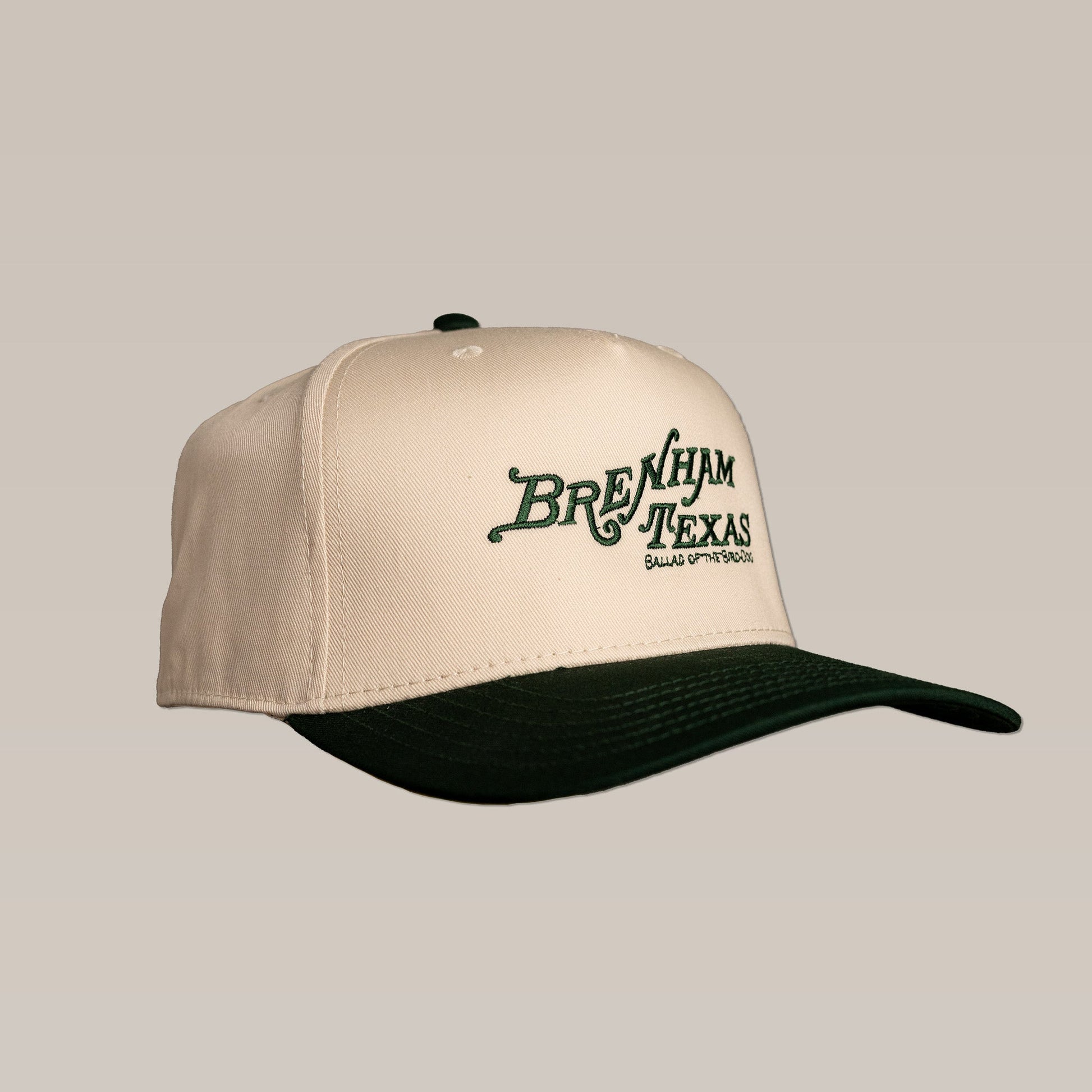 The Shop Hat by Ballad of the Bird Dog features "Brenham Texas" and "Bluebonnet Ground" in green heritage script on a beige and dark green cap—perfect for fans of classic style.
