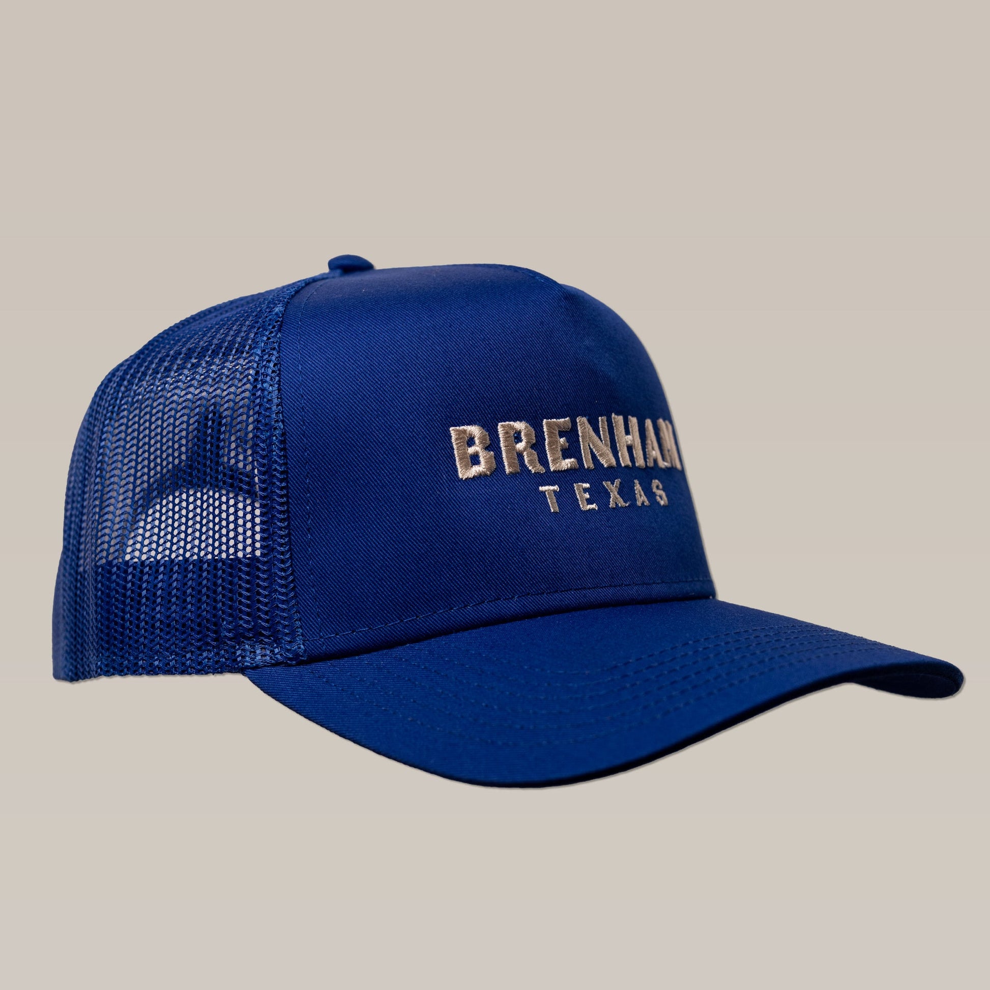 The Shop Hat | Brenham Varsity by Ballad of the Bird Dog is a blue mesh trucker cap with "Brenham Texas" embroidered in white on the front panel, shown against a plain background.