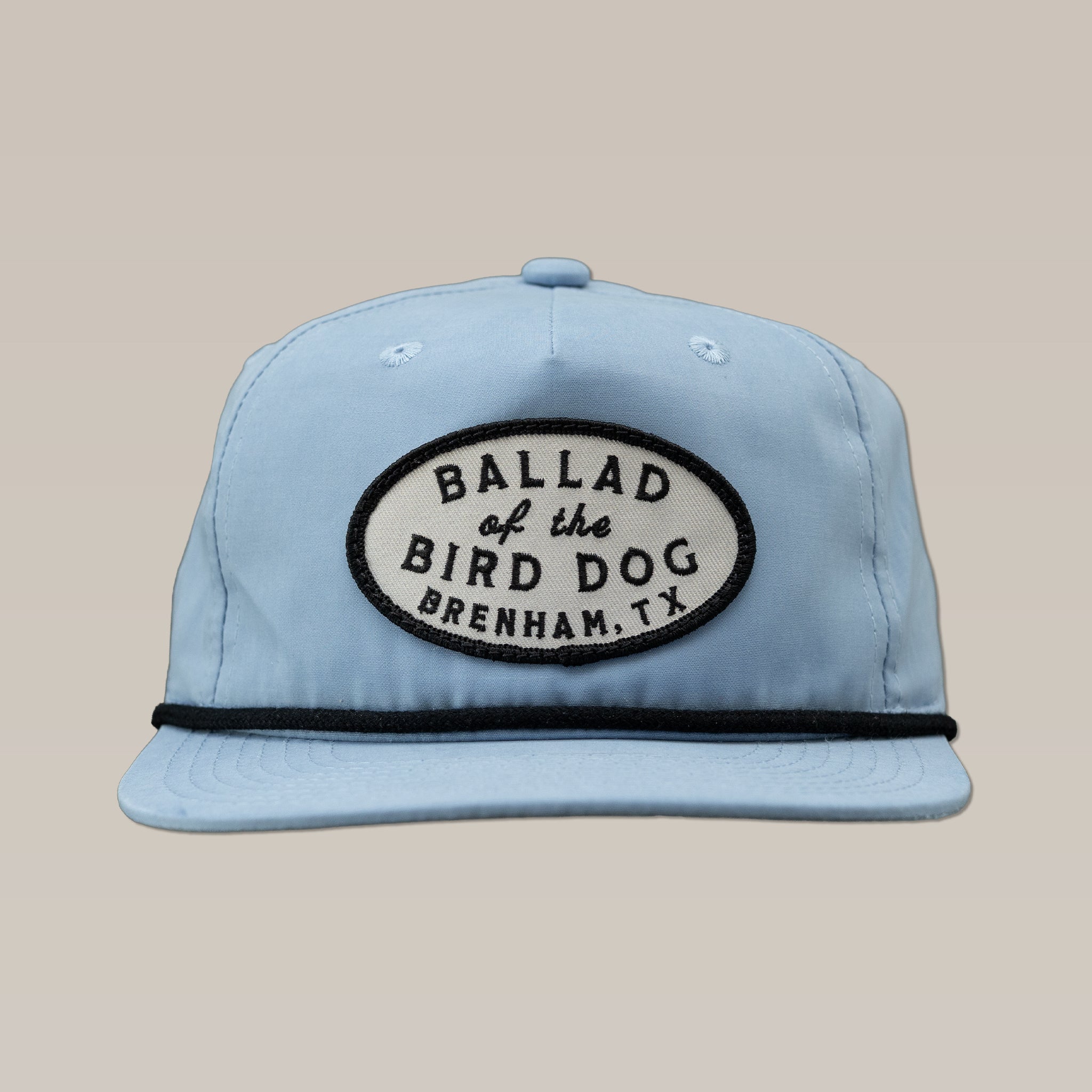 The Ballad of the Bird Dog Shop Hat features a light blue design with a black and white oval patch on the front that reads "BALLAD of the BIRD DOG, BRENHAM, TX.