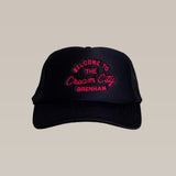 The Shop Hat | Cream City by Ballad of the Bird Dog is a black trucker hat with red embroidered "Welcome to the Cream City Brenham" text—a stylish nod to Brenham, home of Blue Bell Creameries.