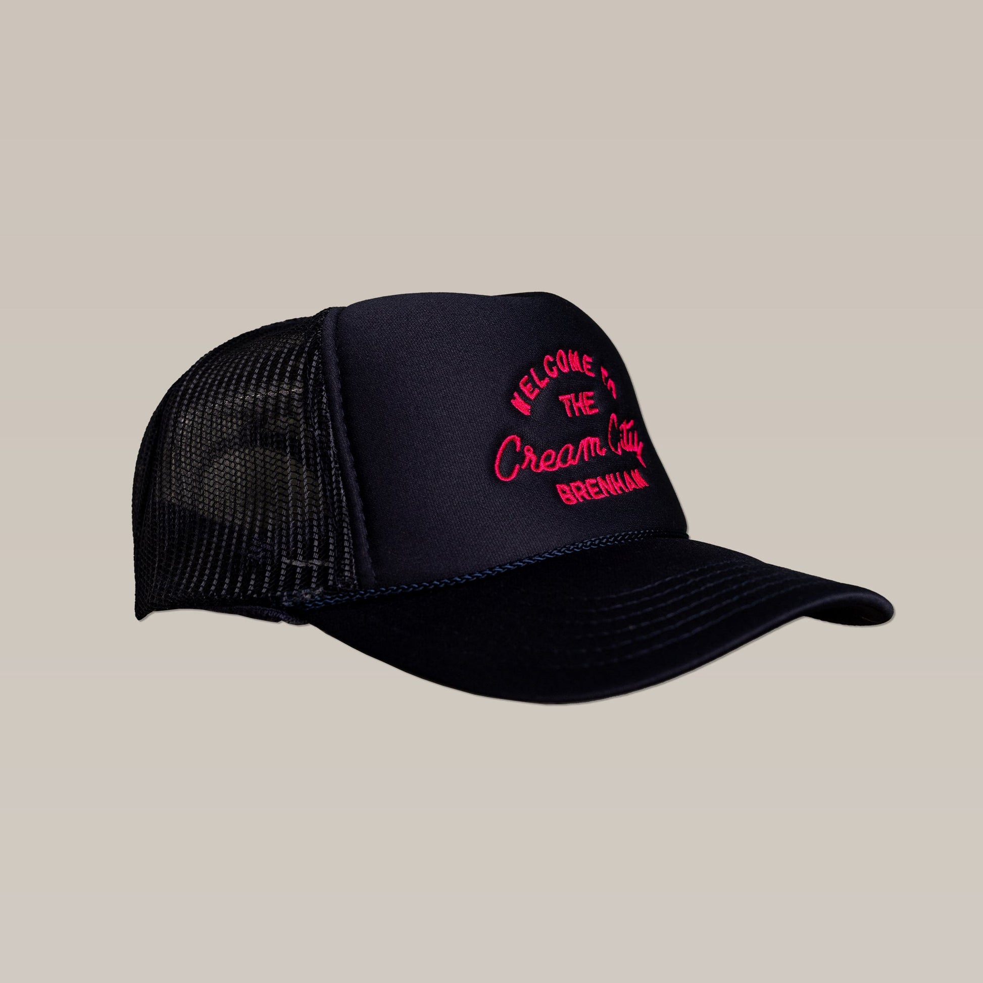 The Shop Hat | Cream City by Ballad of the Bird Dog features black mesh, a curved brim, and pink “WELCOME TO THE Cream City BREWHAUS” embroidery on the front, inspired by Brenham's Blue Bell Creameries.