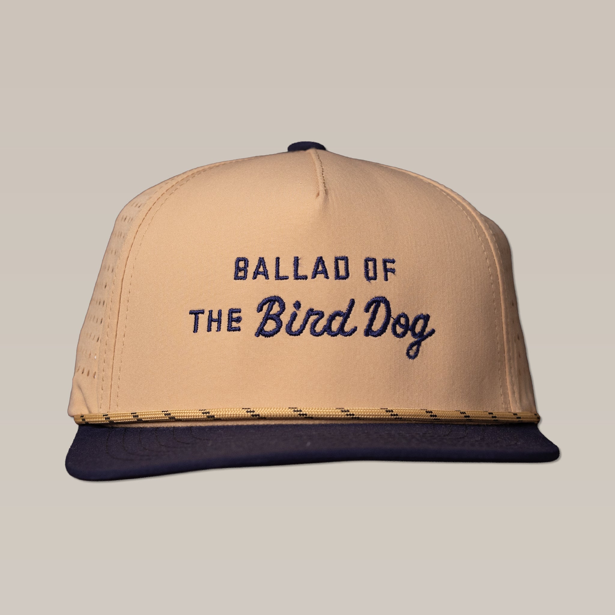 The Ballad of the Bird Dog Shop Hat from the Desert Series is a breathable beige and navy trucker hat with "BALLAD OF THE Bird Dog" embroidered on the front and features sweat-resistant fabric.