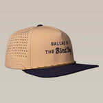 The Ballad of the Bird Dog Shop Hat from the Desert Series features tan and navy colors, "Ballad of the Bird Dog" text on the front, and breathable perforated side panels, shown against a neutral background.
