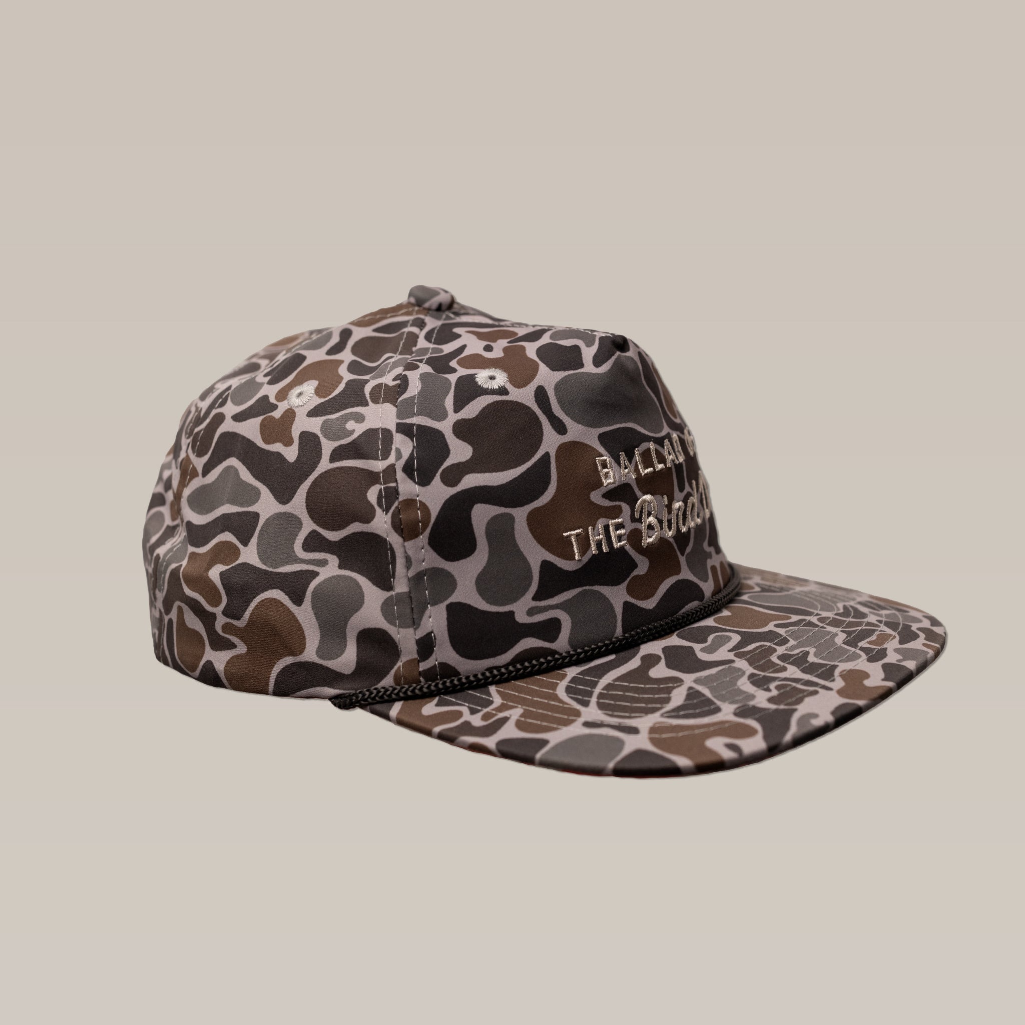 The Shop Hat | Desert Series by Ballad of the Bird Dog is a brown and gray camouflage baseball cap featuring white embroidered text on the front and a small black rope across the brim.