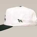 The Shop Hat from Ballad of the Bird Dog's Desert Series features a white crown, dark green brim, and a small embroidered dog on the side.