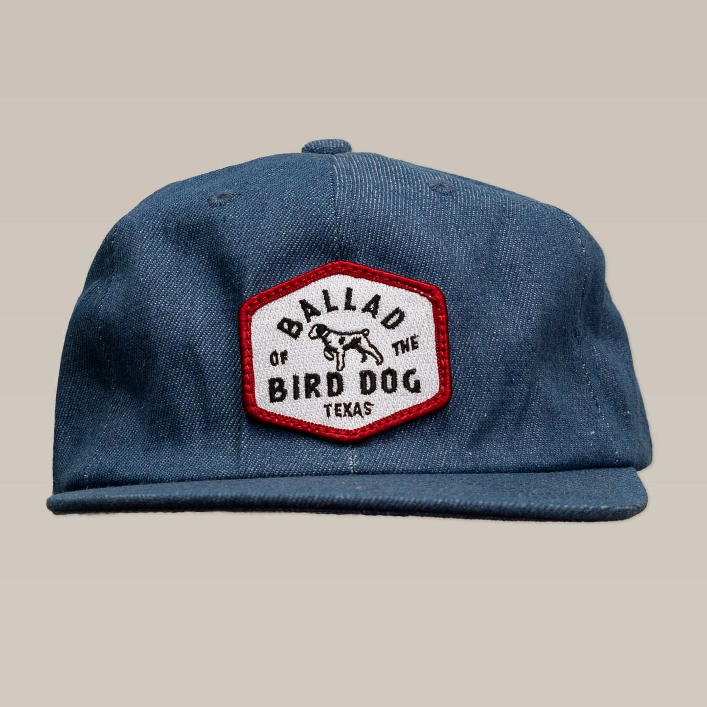The Shop Hat | Field Companion by Ballad of the Bird Dog features a blue design with a unique hexagonal patch displaying a dog graphic and "Ballad of the Bird Dog Texas" text.