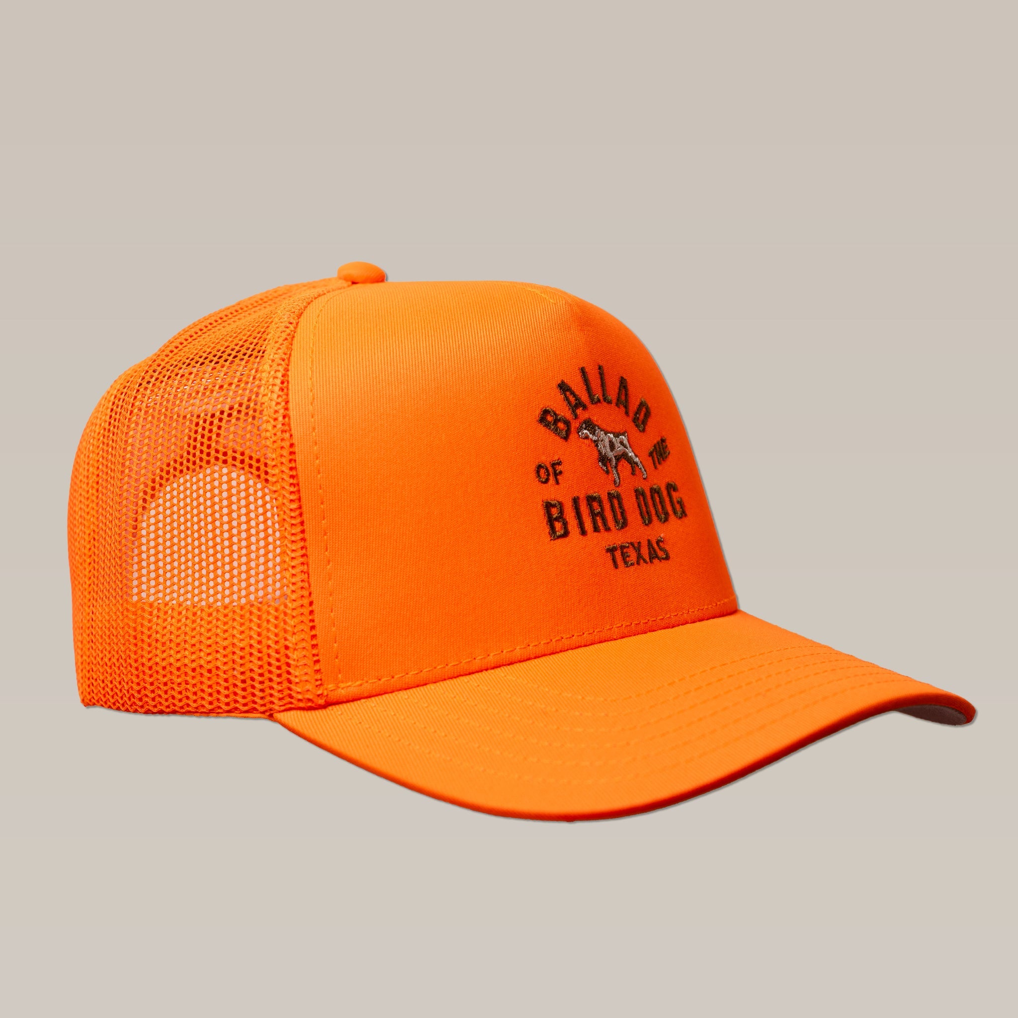 The Shop Hat | Field Companion by Ballad of the Bird Dog is a bright orange mesh trucker cap with "Ballad of Bird Dog Texas" and a dog graphic on the front, shown against a neutral background.