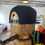 The Shop Hat | Field Companion by Ballad of the Bird Dog is shown on a wooden hat form amid sewing supplies and thread, highlighting the workspace spirit behind this symbolic headwear.