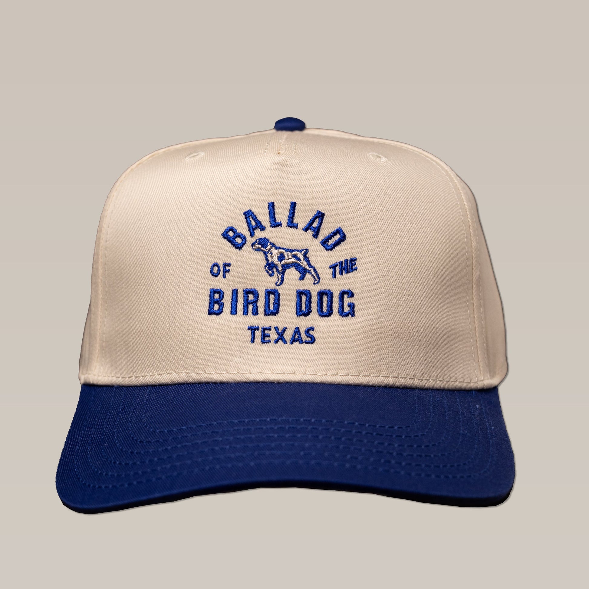 The Ballad of the Bird Dog Shop Hat | Field Companion features a beige and navy design with "Ballad of the Bird Dog Texas" and a dog embroidered on the front.