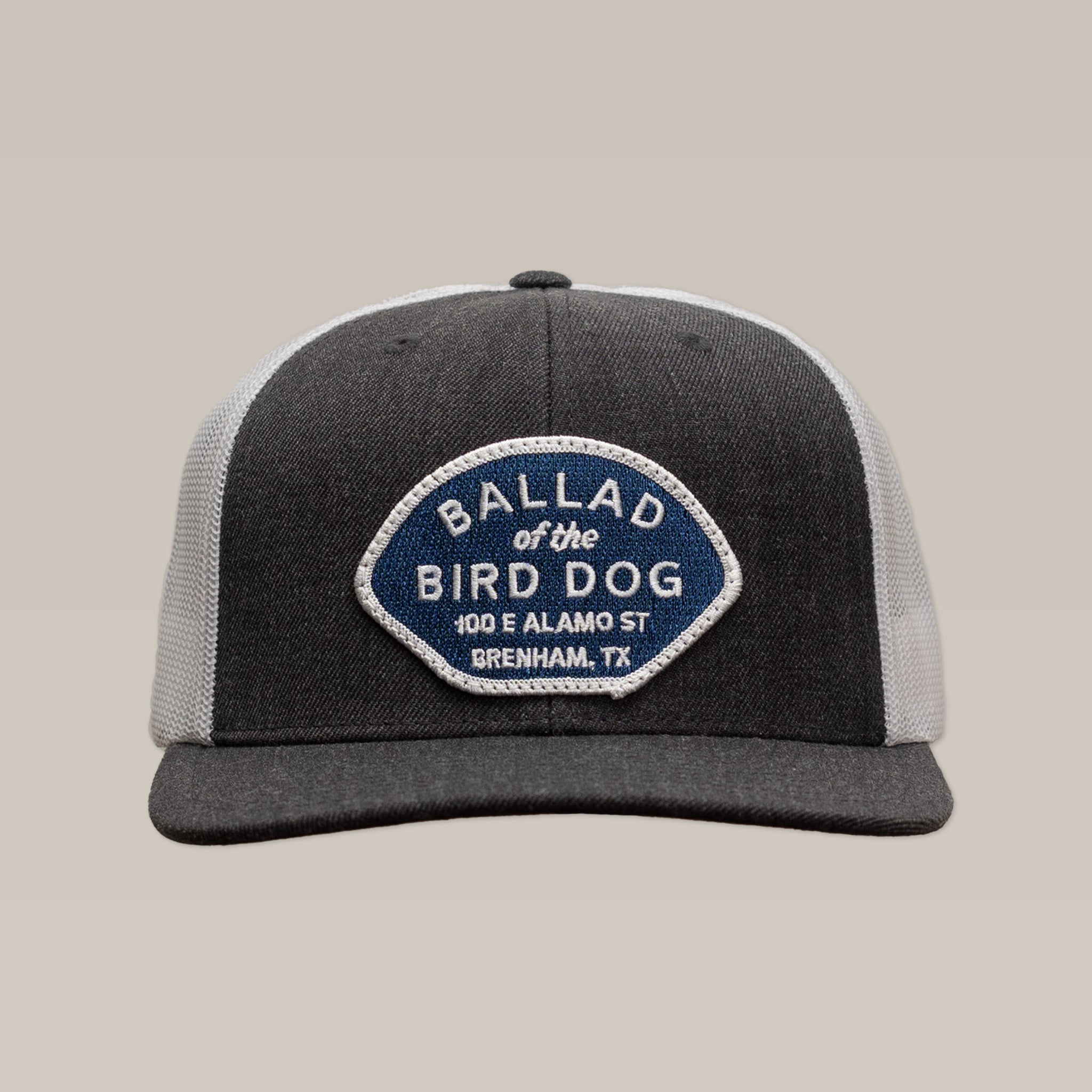 Show your local pride with the Shop Hat | Home Base by Ballad of the Bird Dog—a gray and white hat featuring a blue and white patch reading "Ballad of the Bird Dog, 100 E Alamo St, Brenham, TX" on the front. Perfect for supporting small businesses!.