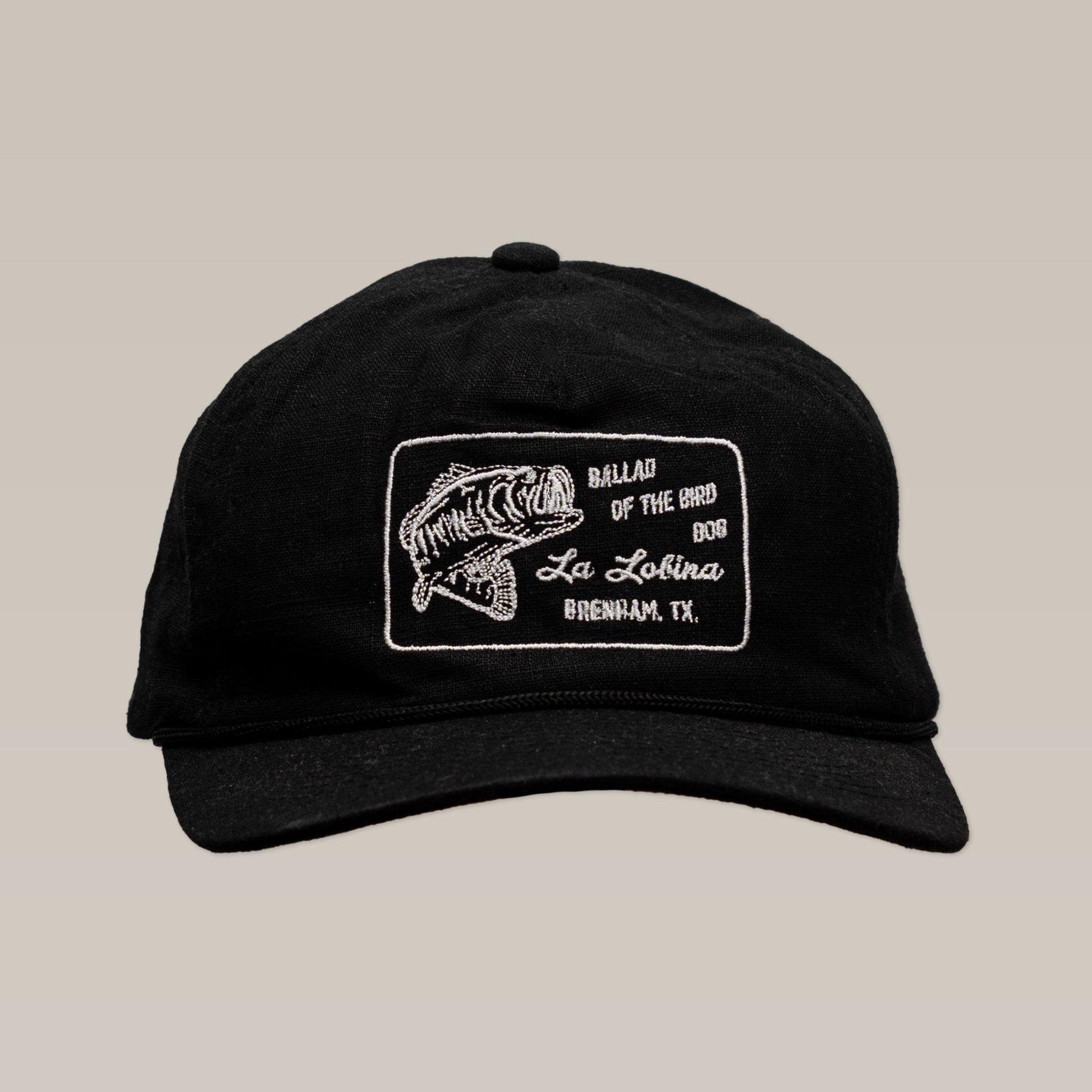 The Ballad of the Bird Dog Shop Hat | La Lobina is a black angler hat with a white embroidered fish patch and "Ballad of the Bird Dog" branding.