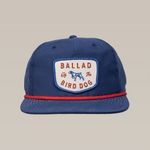 The Ballad of the Bird Dog Shop Hat | Legend features a blue design with red trim, a white patch reading "Ballad of the Bird Dog," and a blue dog silhouette—ideal for fans of the legend or vintage hunting hat style.
