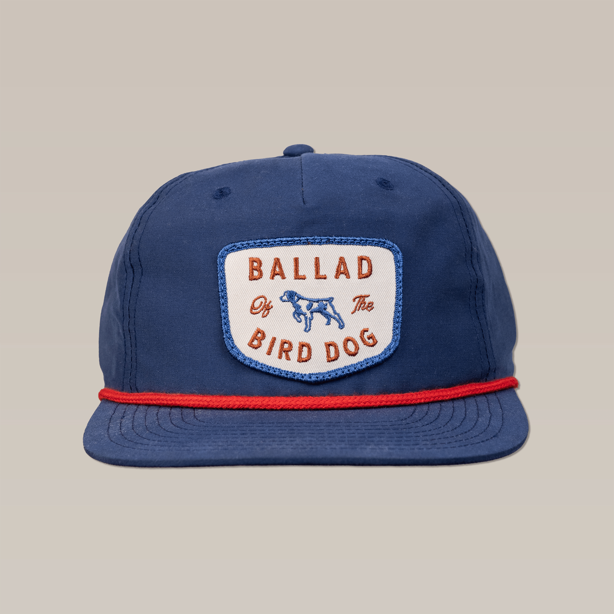 The Shop Hat | Legend by Ballad of the Bird Dog is a blue cap with a white "Ballad of the Bird Dog" patch, blue dog illustration, red cord above the brim, and vintage Americana hunting hat style.