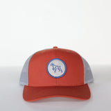 The Shop Hat | Merit Badge by Ballad of the Bird Dog is a red and gray snapback trucker hat featuring a circular patch with a bird dog silhouette on the front.