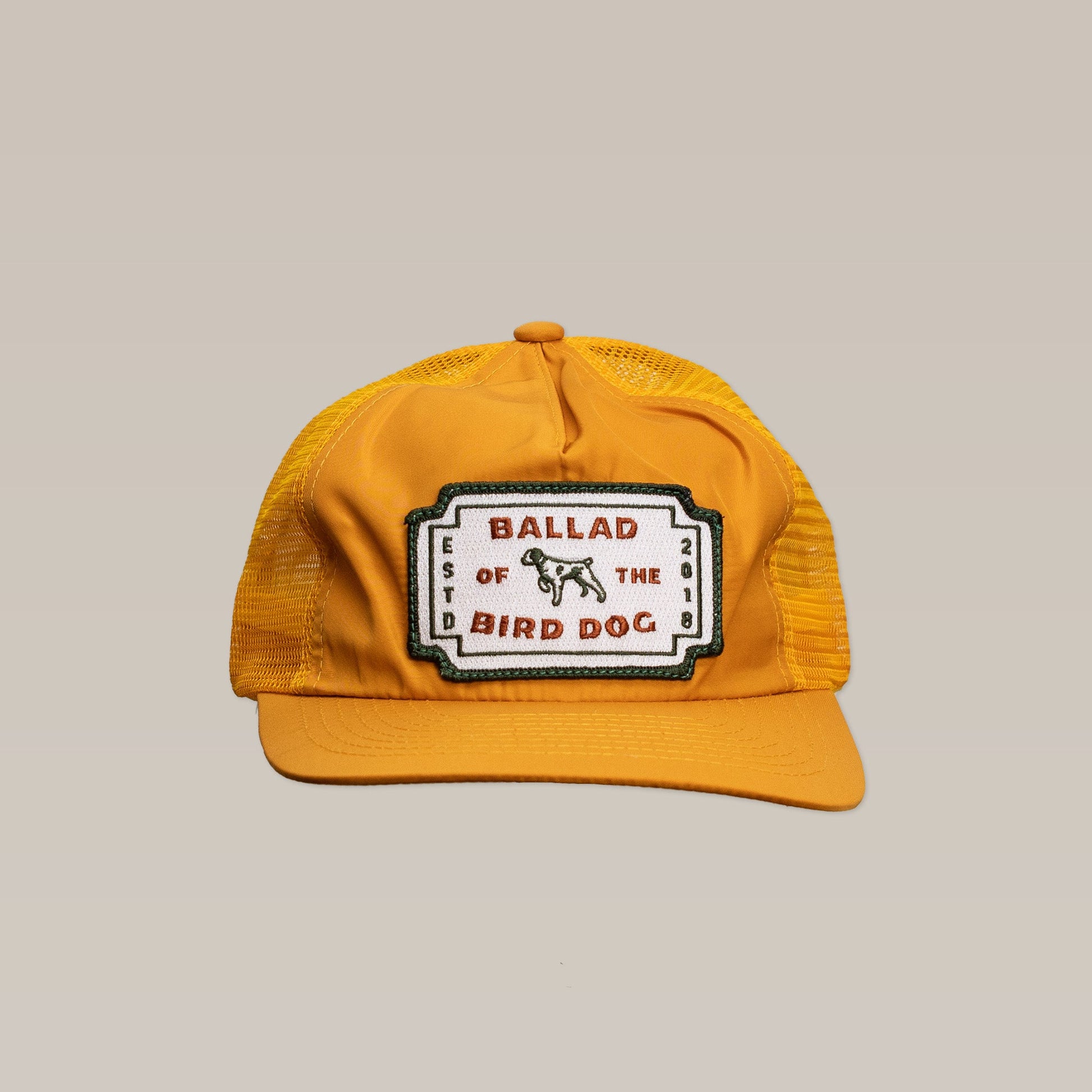 Show your Brenham pride with the Shop Hat | Neon Revival by Ballad of the Bird Dog—a yellow mesh trucker hat with a classic logo patch, "Ballad of the Bird Dog Est. 2018," and a small dog graphic.