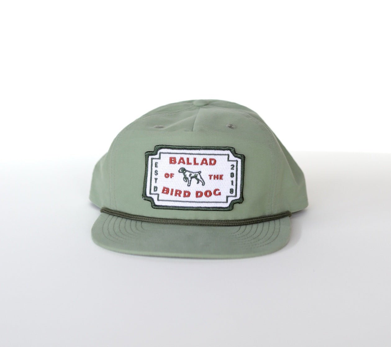 The Ballad of the Bird Dog Shop Hat | Neon Revival features a light green hue, a classic logo patch with "BALLAD OF THE BIRD DOG" and a small dog illustration, inspired by downtown Brenham style.