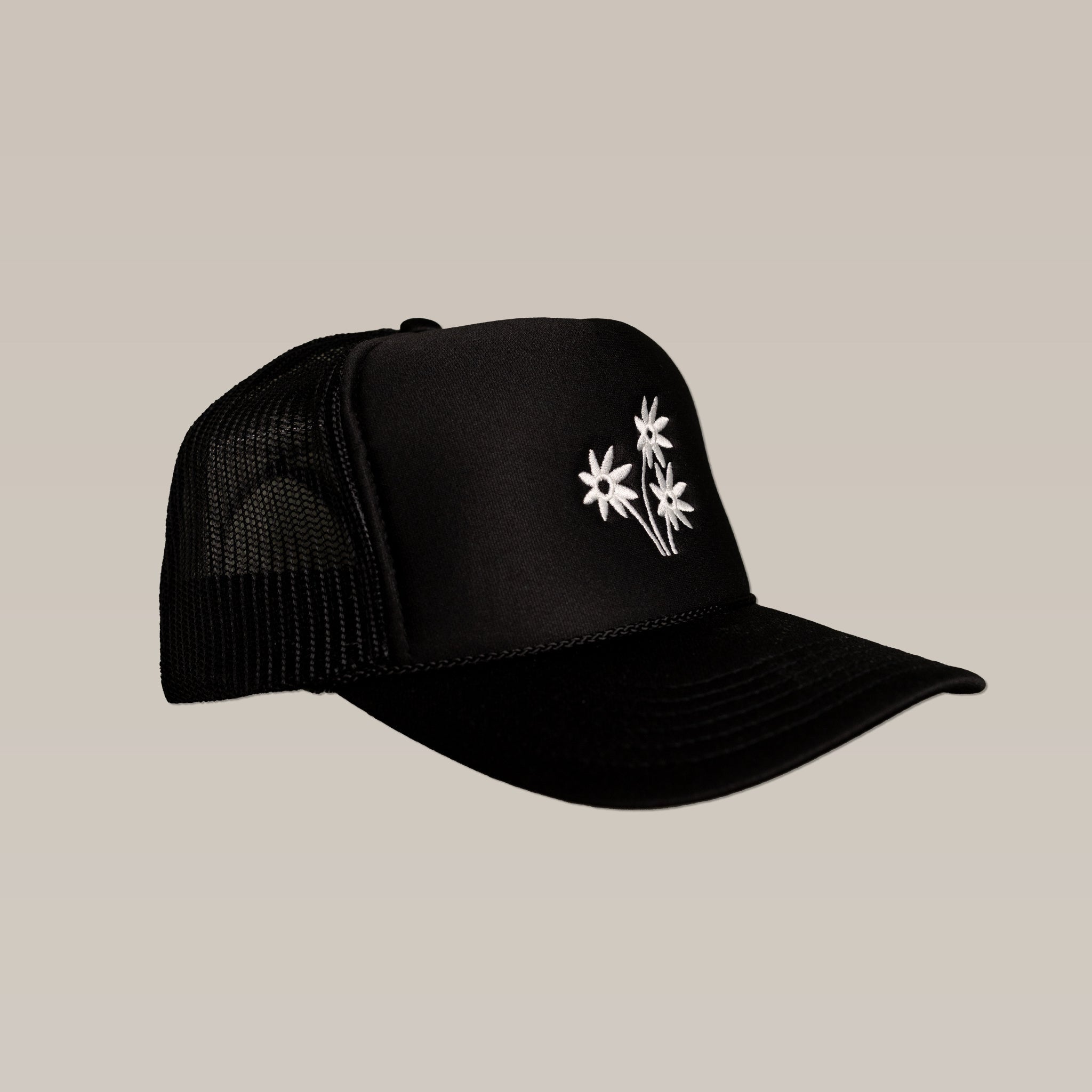 The Shop Hat | Peace Flower by Ballad of the Bird Dog features black mesh and three white embroidered peace flowers on the front—a stylish accessory to elevate any outfit.
