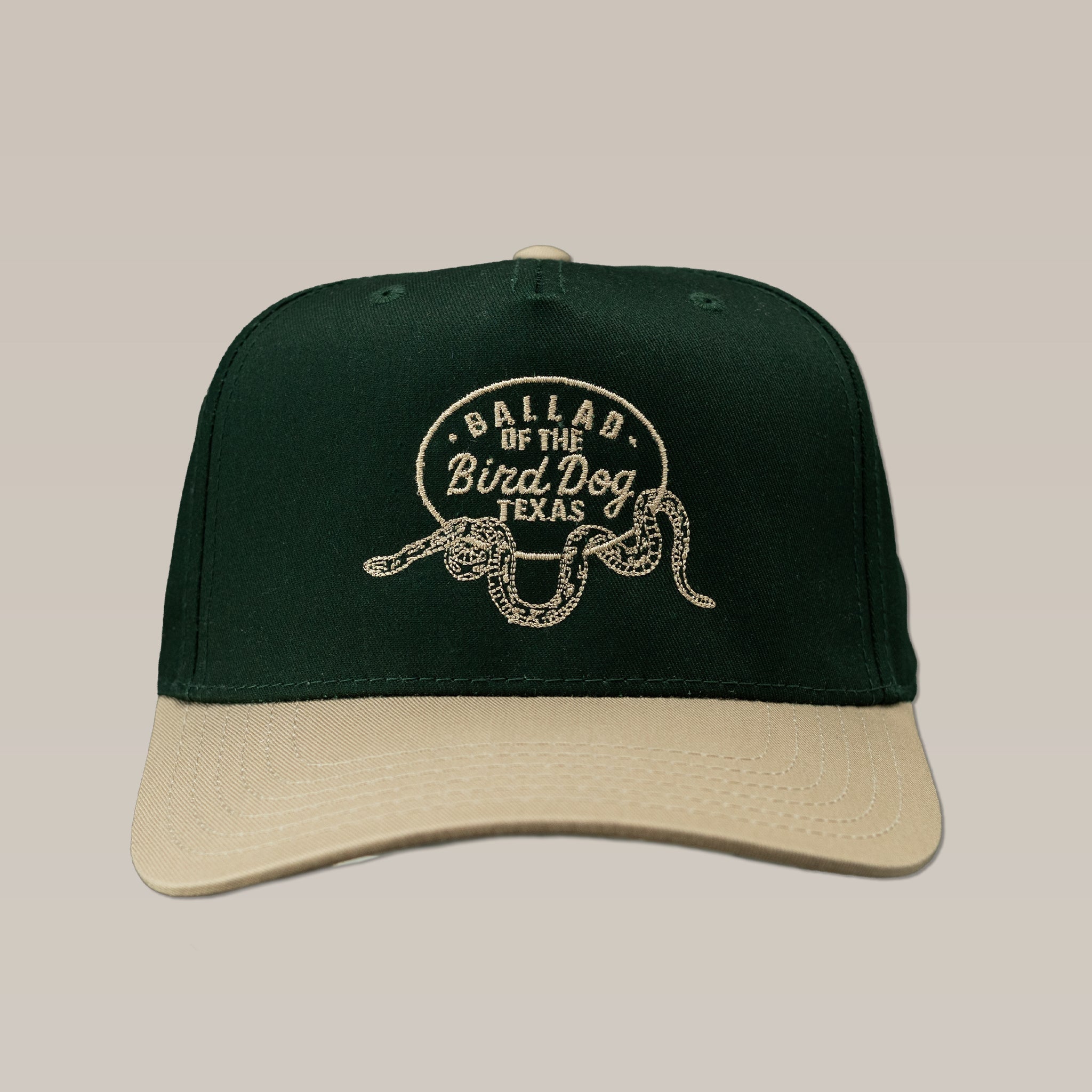 Dark green and beige Shop Hat by Ballad of the Bird Dog featuring an embroidered Rattlesnake Oval Logo and "Ballad of The Bird Dog Texas" on the front.