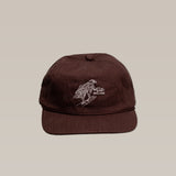 The Shop Hat | Red Tailed Hawk by Ballad of the Bird Dog is a brown baseball cap featuring a white embroidered bird design on the front, shown against a plain beige background.