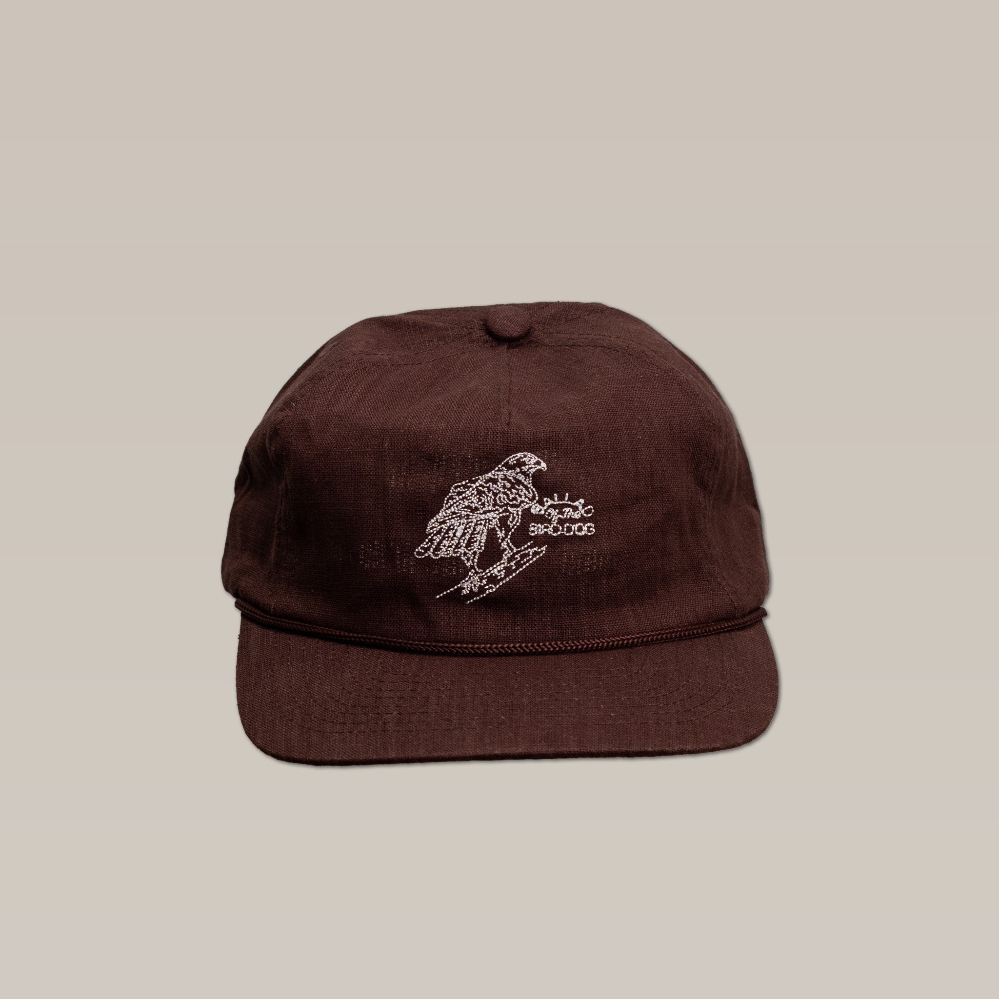 The Shop Hat by Ballad of the Bird Dog is a brown baseball cap featuring an embroidered red-tailed hawk perched on a branch, shown against a plain beige background.