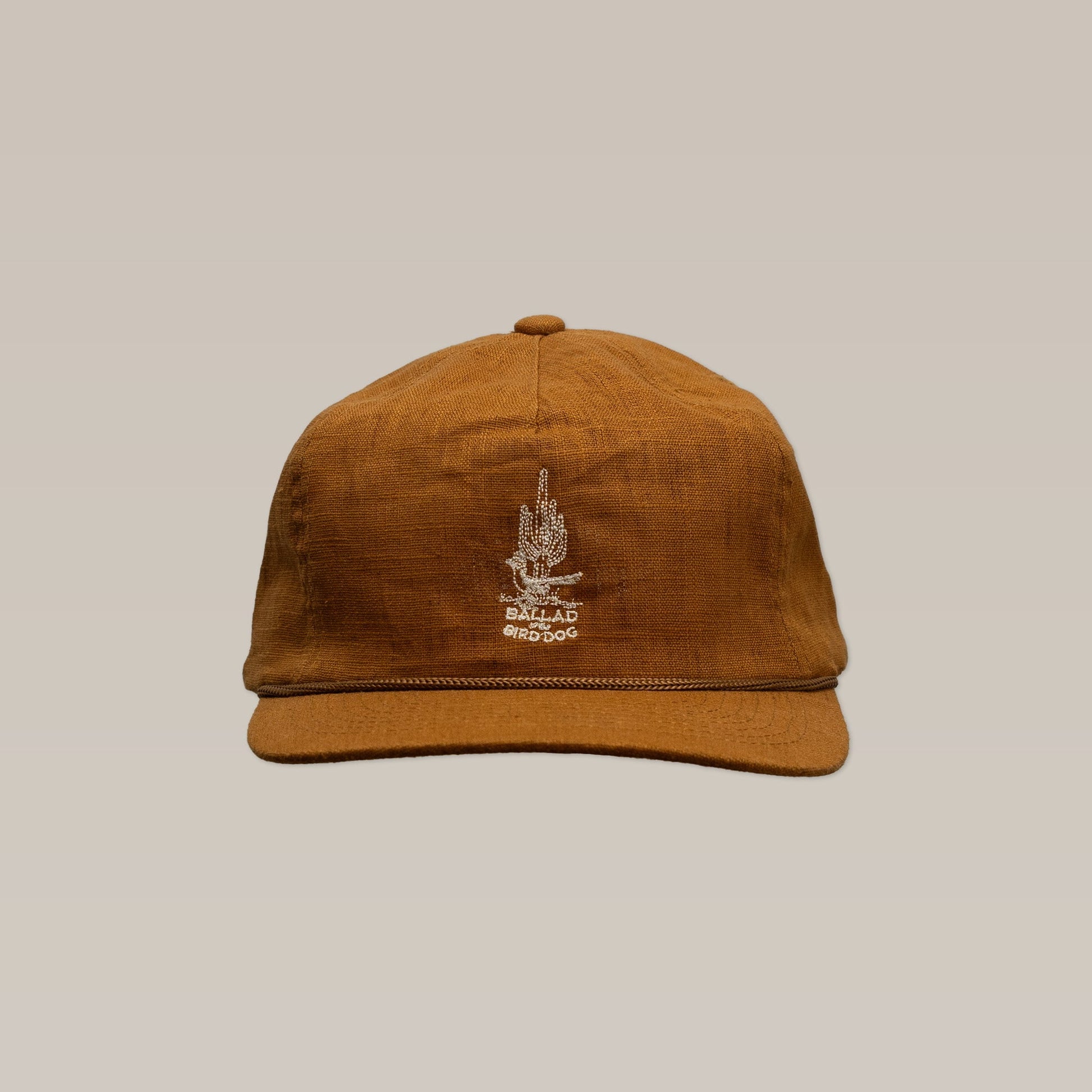 The Shop Hat | Roadrunner Saguaro by Ballad of the Bird Dog features an embroidered white design and text on the front, shown against a plain beige background.