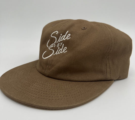 The Shop Hat | Side by Side by Ballad of the Bird Dog features brown fabric and white "Side by Side" embroidery—an ideal accessory celebrating bird dog companionship and quality goods, showcased on a plain white background.