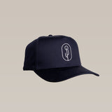 The Shop Hat | Simple Saguaro by Ballad of the Bird Dog is a black cap with a white minimalist embroidered saguaro cactus logo on the front, shown against a plain beige background.
