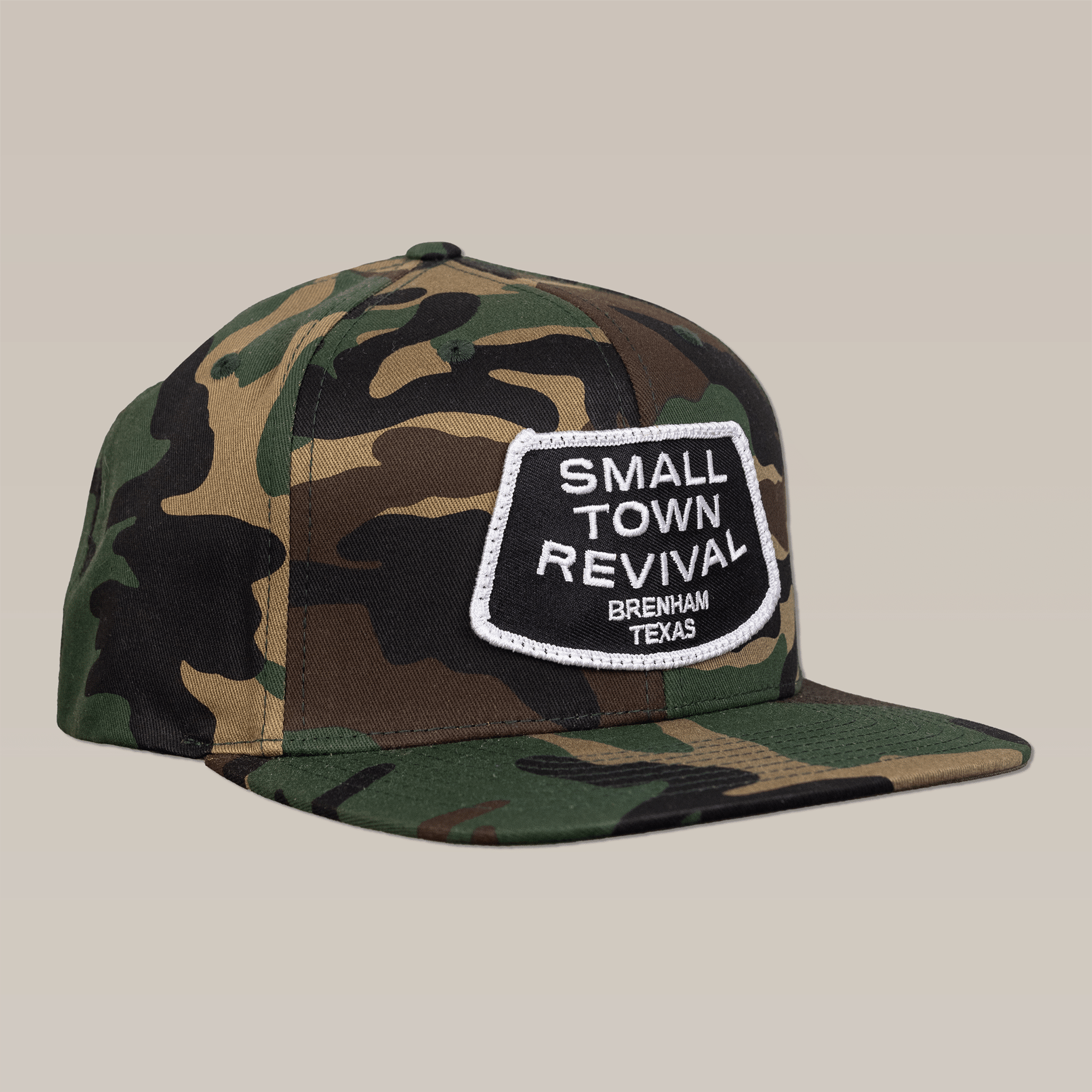 The Shop Hat by Ballad of the Bird Dog features a camo snapback and a "SMALL TOWN REVIVAL, BRENHAM TEXAS" patch—ideal for fans of small town style and Brenham-inspired hats.