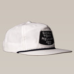 The Ballad of the Bird Dog Shop Hat features a black "Small Town Revival Brenham Texas" patch on a white snapback, perfect for small town patch hat fans. Shown on a plain beige background.