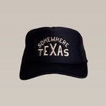 The Ballad of the Bird Dog Shop Hat, designed by Carra Sykes, is a black snapback with mesh sides and "Somewhere Texas" embroidered in white—combining comfort and style for any adventure.