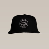 The Ballad of the Bird Dog Shop Hat | Trust Your Gut features a black mesh SnapBack and a round white patch that reads "BALLARD THE BIRD DOG TRUST YOUR GUT OPENHAWM TX," delivering bold style and comfort.