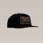 The Shop Hat | Trust Your Gut Vintage Slate by Ballad of the Bird Dog is a black snapback featuring a rectangular patch with "BALLAD OF THE BIRD DOG" and "TRUST YOUR GUT" in yellow and white for classic style.